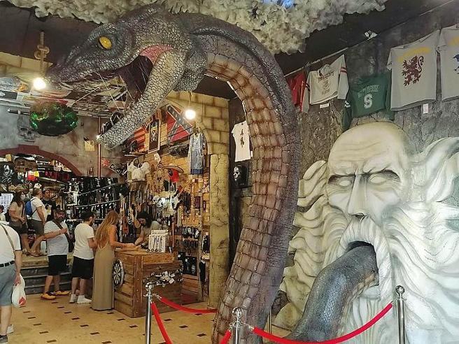 Un negozio veronese con la statua di un serpente gigante e un bassorilievo con la bocca spalancata.